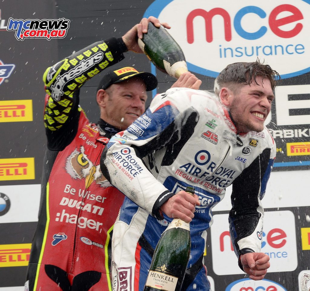 Shane Byrne congratules Jake Dixon on his Knockhill win with a dousing of champagne