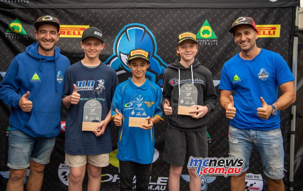 2022 FIM MiniGP Australia Series Round 1 Podium - Teering Fleming the winner alongside Harrison Watts and Levi Russo. The competitors are flanked by Wayne Maxwell's fellow series organisers Nick Angelopolous and Dimitrios Papaconstantinou - Image RbMotoLens