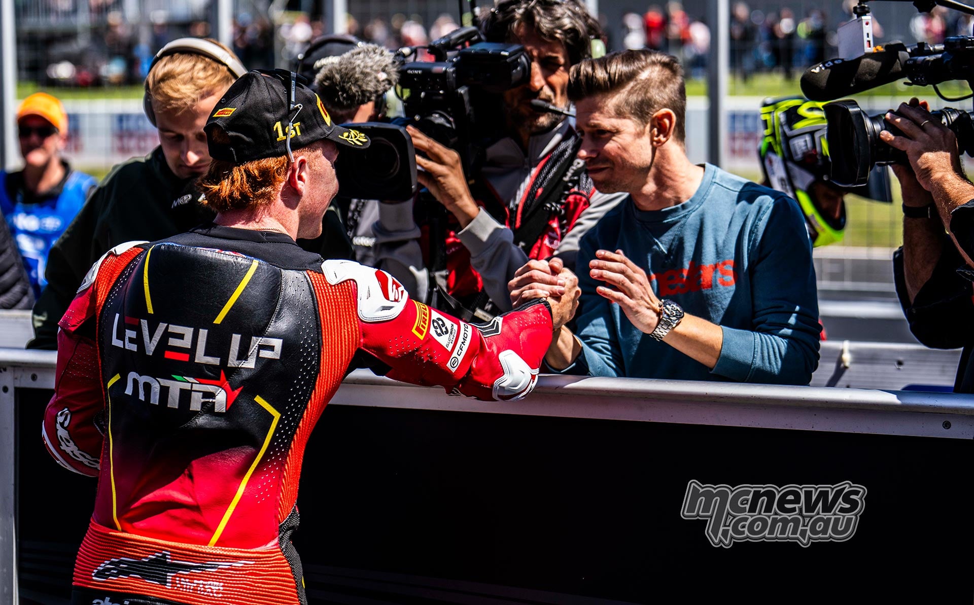 Joel Kelso shakes hands with Casey Stoner in parc ferme after taking Moto3 pole at Phillip Island in 2025.