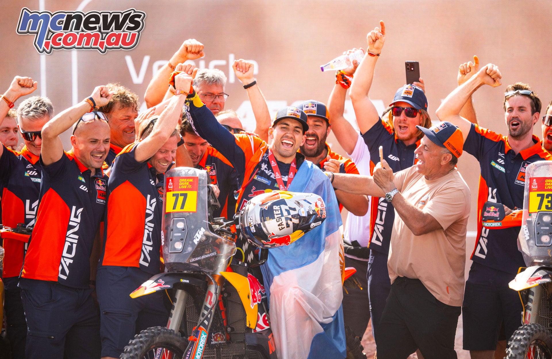 Luciano Benavides celebrates his 2026 Dakar victory with the Red Bull KTM team around his number 77 motorcycle.