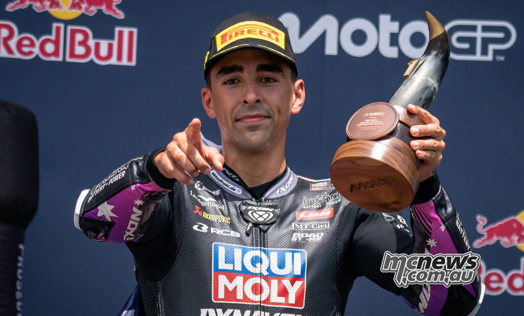 Senna Agius points toward the camera while holding the Moto2 winner’s trophy on the podium at Circuit of The Americas.