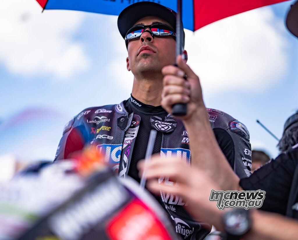 Close-up portrait of Senna Agius on the grid at COTA wearing sunglasses and holding an umbrella above his Intact GP leathers.
