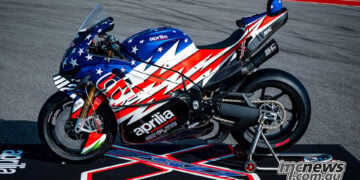 Full side profile of the Aprilia X 250TH on paddock stands showing the stars-and-stripes livery and RSV4-based silhouette.