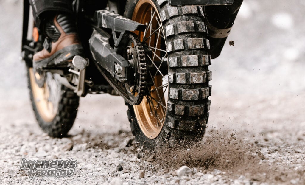 Close-up of a Continental TKC 80² tyre throwing gravel on a loose dirt surface.