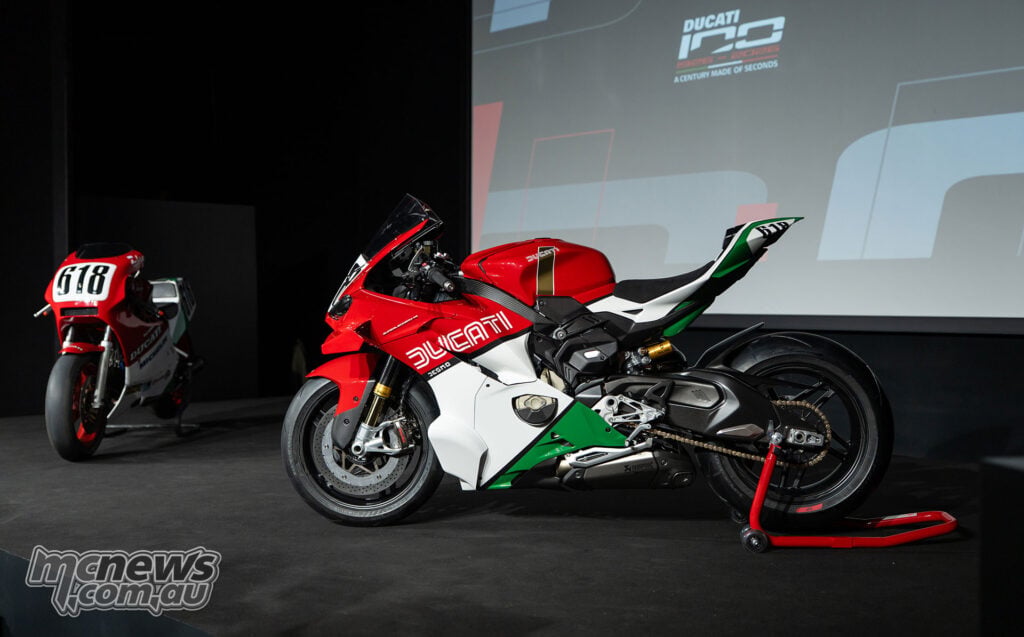 Side view of Ducati Superleggera V4 Centenario Tricolore on a paddock stand with a classic Ducati race bike behind.