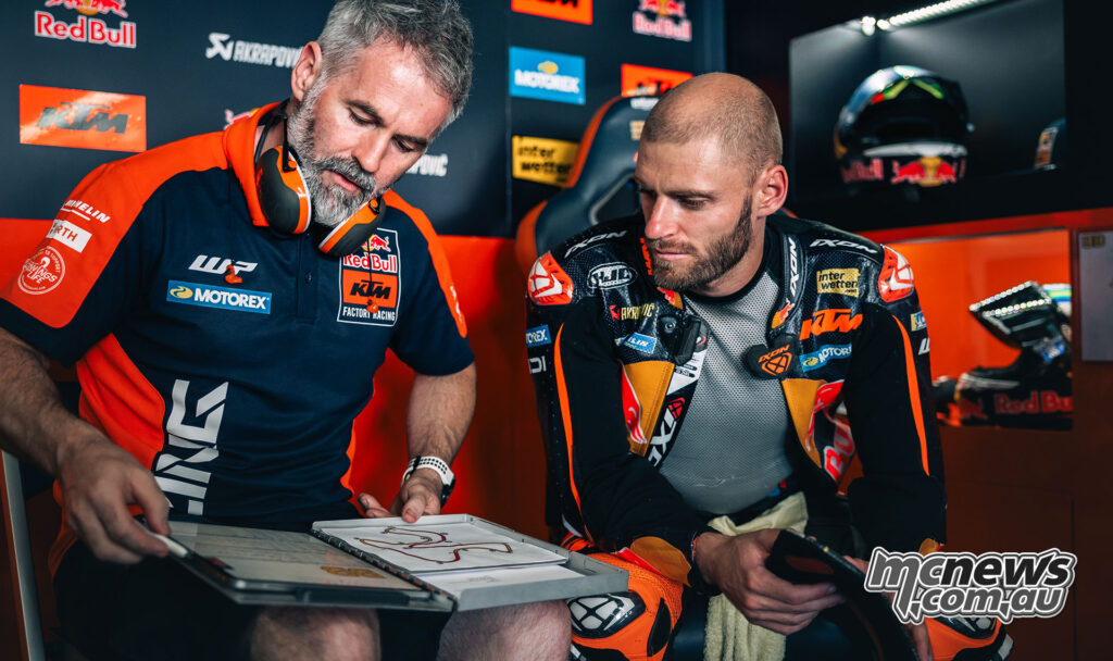 Brad Binder studies setup notes with a KTM engineer inside the Jerez pit garage.