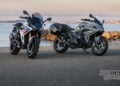 Two BMW R 1300 RS motorcycles parked by the waterfront at sunset
