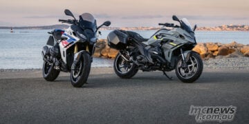 Two BMW R 1300 RS motorcycles parked by the waterfront at sunset