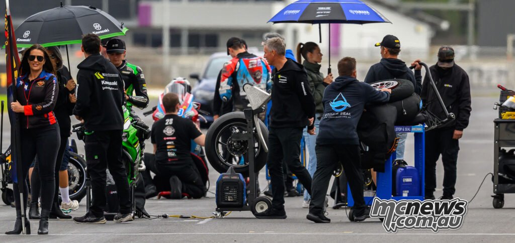 ASBK Supersport and Next Gen teams preparing bikes on the grid before a wet-declared Race Two at The Bend