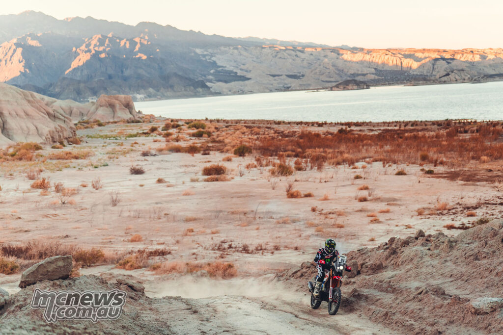 Martim Ventura rides a Honda rally bike along a rocky track beside a lake in Argentina.
