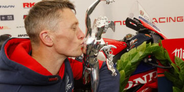 Dean Harrison kissing the Senior TT trophy in the Honda Racing awning.