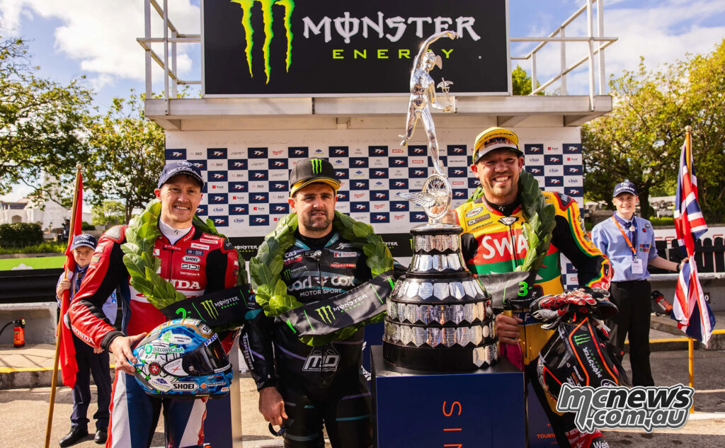 Dean Harrison, Michael Dunlop and Peter Hickman stand on the Supersport TT Race 1 podium with the trophy.