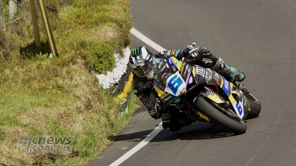 Michael Dunlop leans his Ducati Panigale V2 close to a stone wall during the Supersport TT.