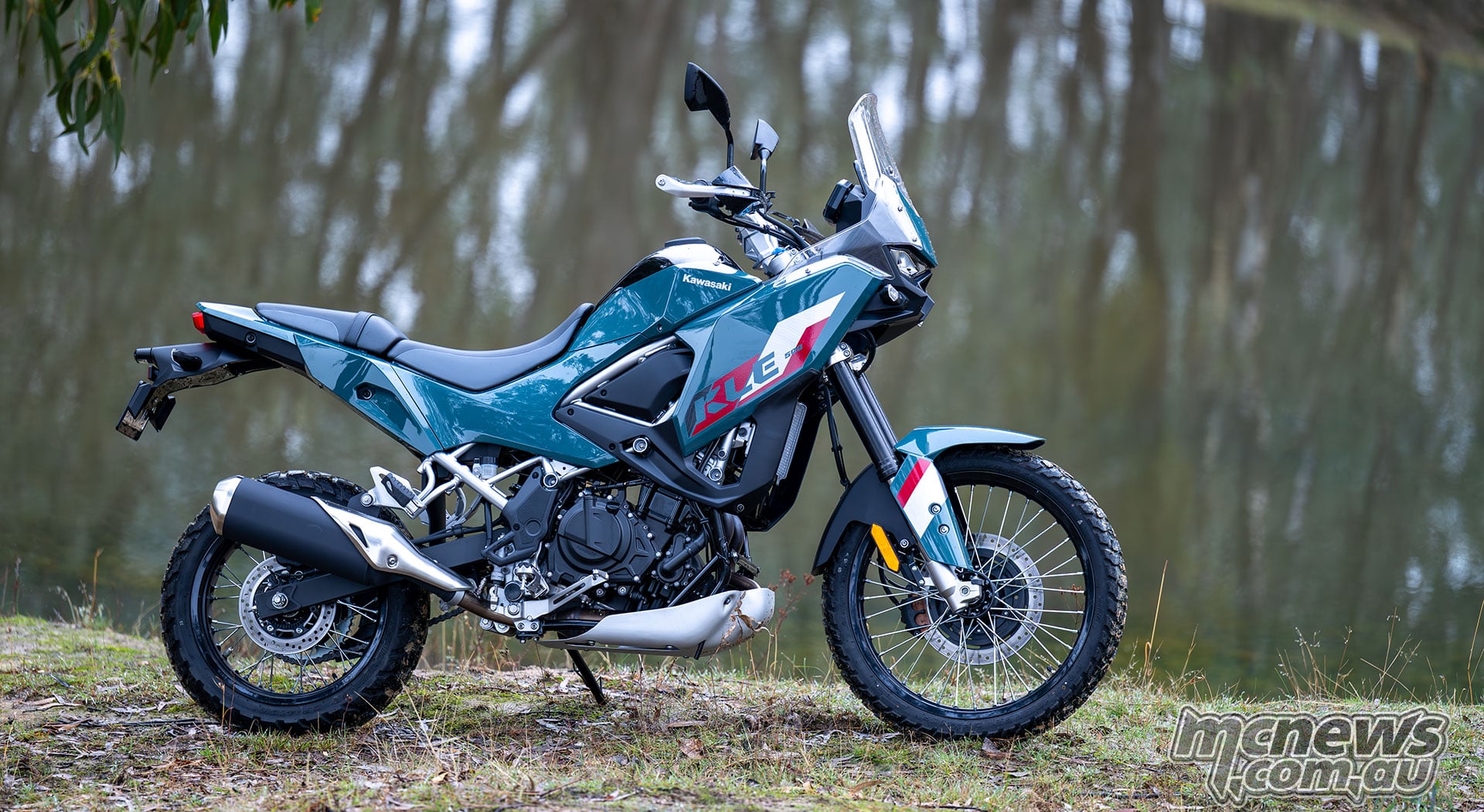 Blue-green Kawasaki KLE500 SE parked beside a dam, viewed from the right side.