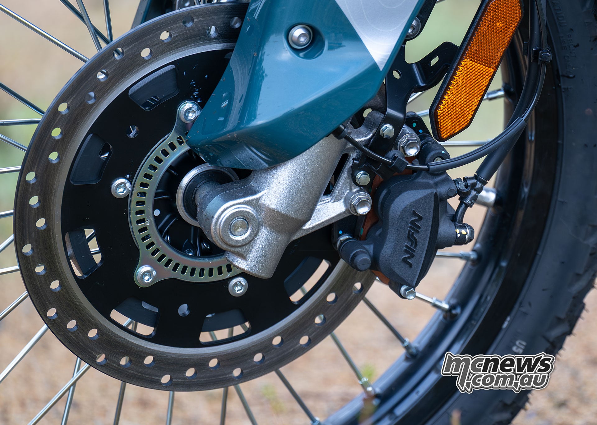Close-up of the Kawasaki KLE500 SE front brake disc, Nissin caliper, ABS sensor ring and spoked wheel.