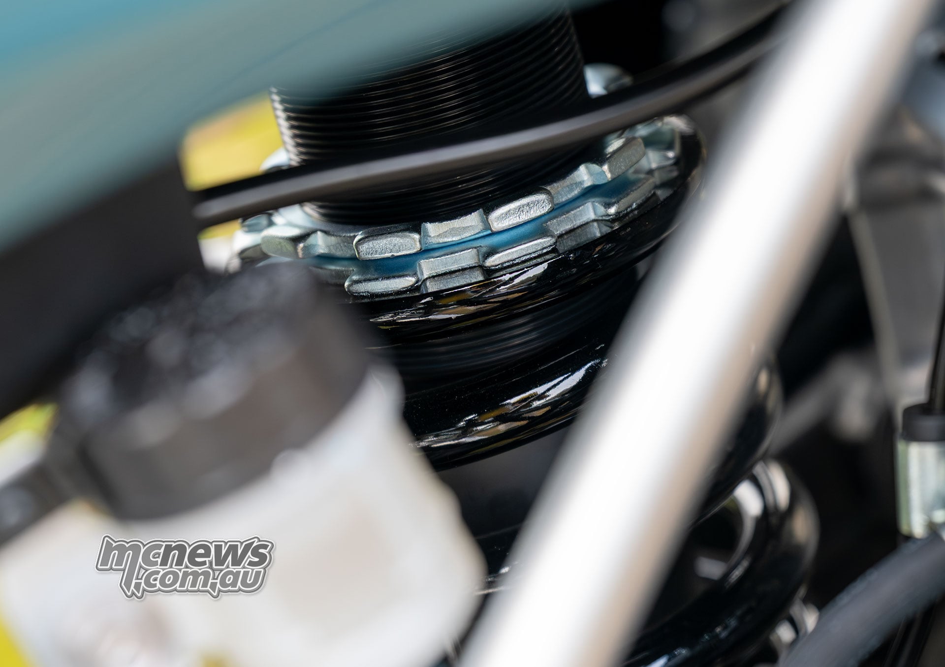 Close-up of the Kawasaki KLE500 SE rear shock spring and threaded preload adjustment collars behind the frame.