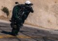 Landscape image of the 2026 Kawasaki Z1100 SE ABS carrying a high wheelie on a twisty road.