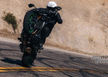 Landscape image of the 2026 Kawasaki Z1100 SE ABS carrying a high wheelie on a twisty road.