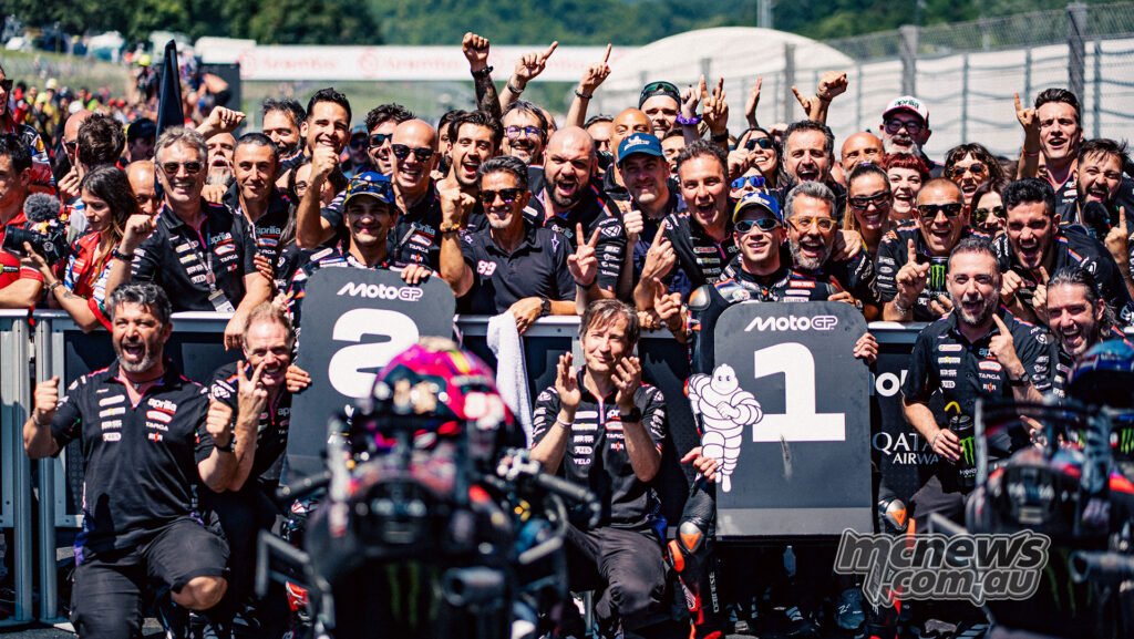 Aprilia Racing team members celebrate in parc ferme with first and second place boards at Mugello.