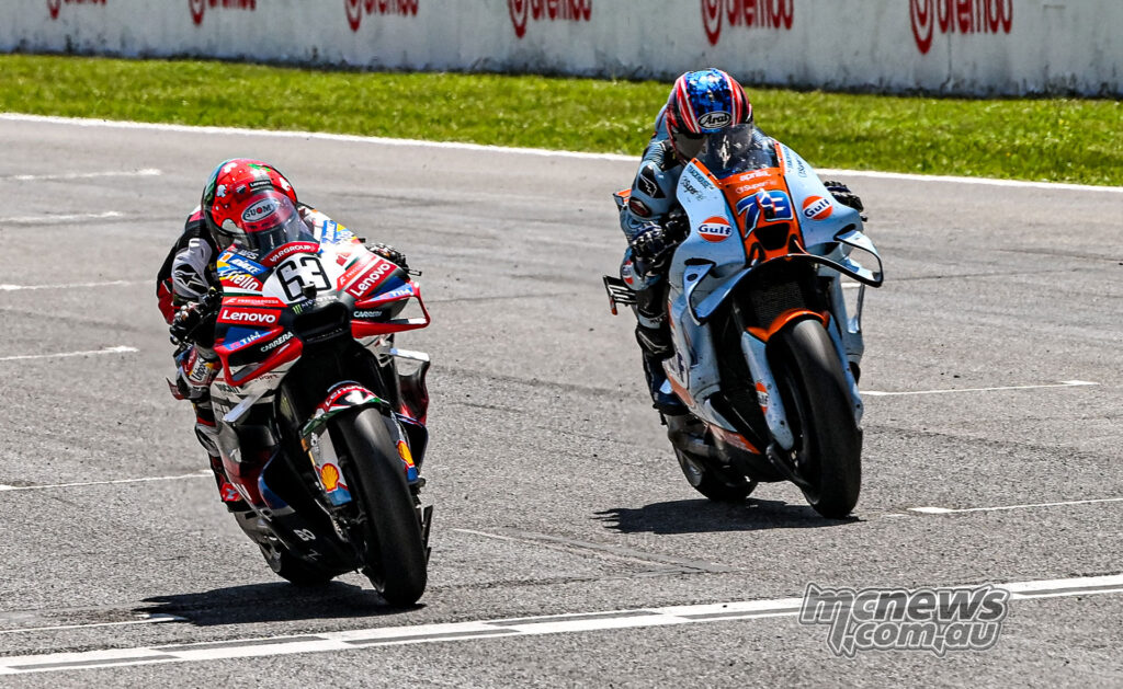 Francesco Bagnaia and Ai Ogura race side by side across the Mugello finish line.