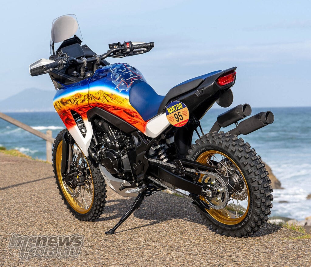 Rear three-quarter view of Honda XL750 Transalp Dakar Tribute custom with twin exhausts and gold wheels