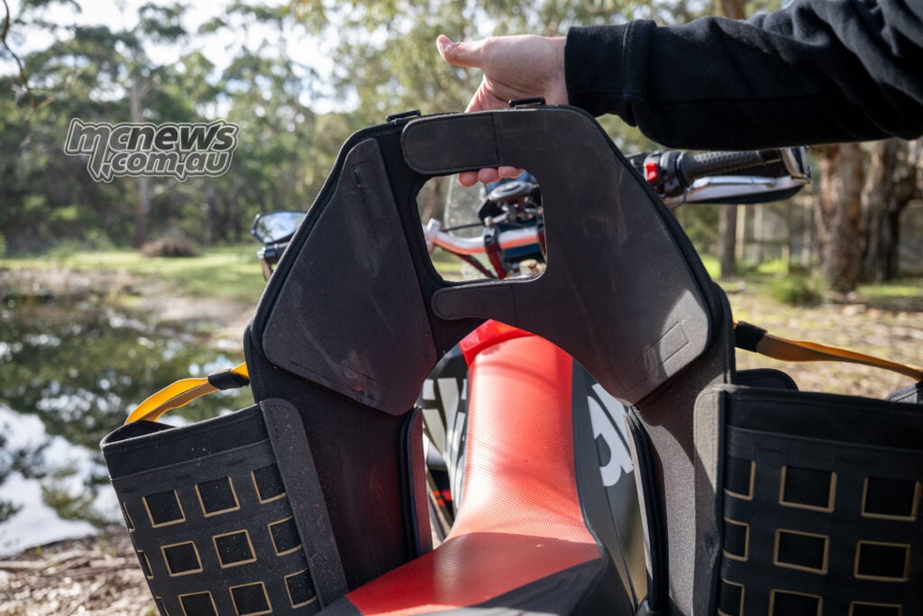 Hands installing a removable Givi Canyon side bag into its rackless mounting cradle.