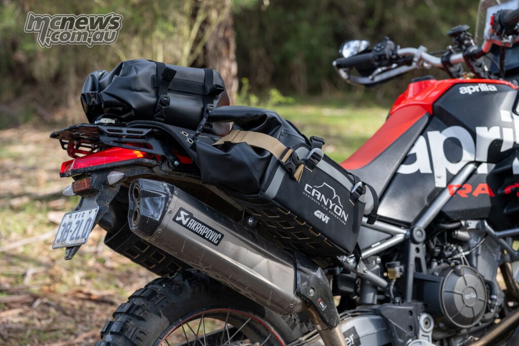 Close-up of compression straps securing black Givi Canyon luggage to an Aprilia Tuareg 660.