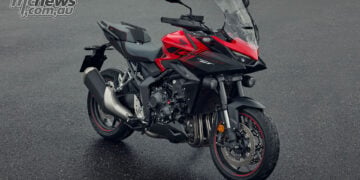 Front three-quarter view of a red 2026 Honda CB1000GT with hand guards, windscreen and auxiliary lights.