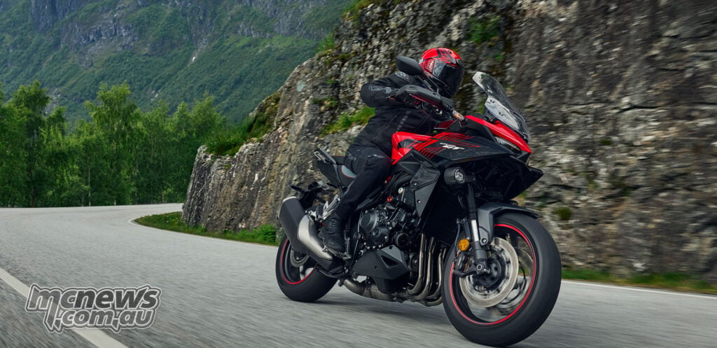 Rider cornering on a red 2026 Honda CB1000GT along a winding mountain road.
