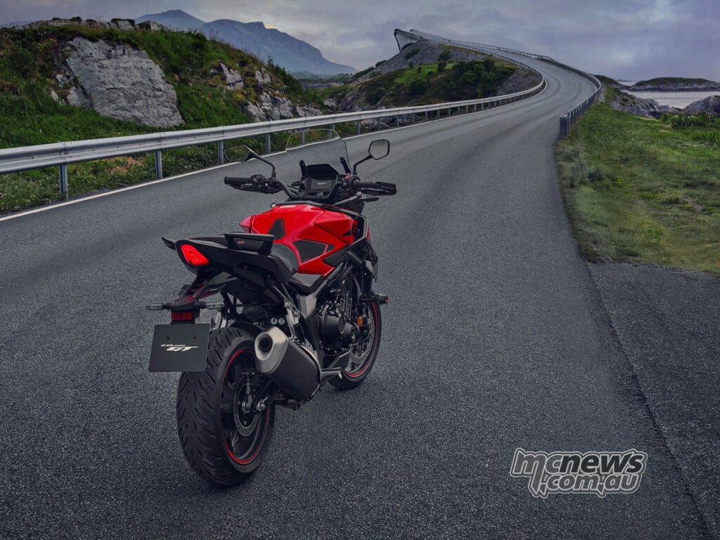 Elevated rear view of the 2026 Honda CB1000GT facing an empty winding road through a coastal landscape.