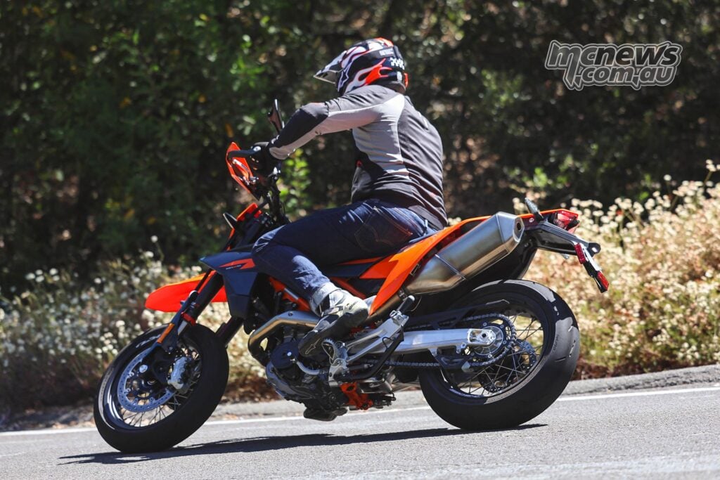Test rider cornering the 2026 KTM 690 SMC R on a tight, tree-lined road.