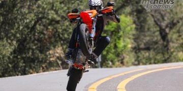 2026 KTM 690 SMC R lifting the front wheel on a winding road during road test.