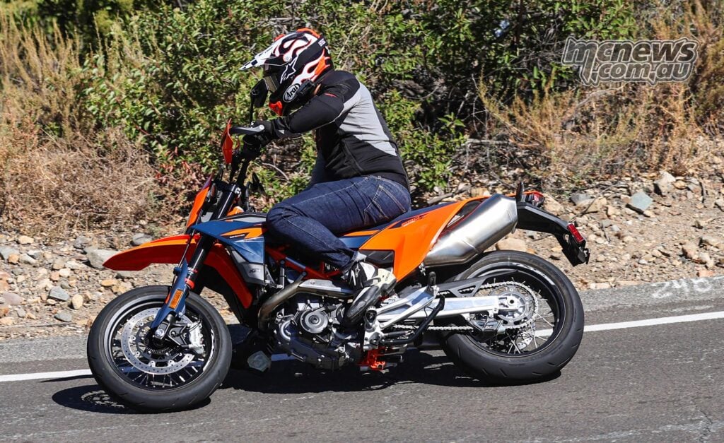 2026 KTM 690 SMC R ridden along a mountain road, showing its tall supermoto stance and slim bodywork.