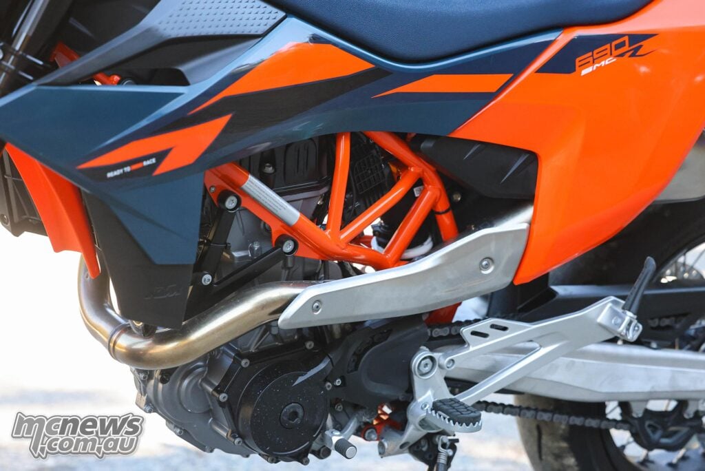 Side detail of the KTM 690 SMC R showing the seat, bodywork, trellis frame, exhaust and swingarm.