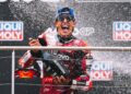Marc Marquez sprays a large bottle of sparkling wine during the German MotoGP podium celebration.