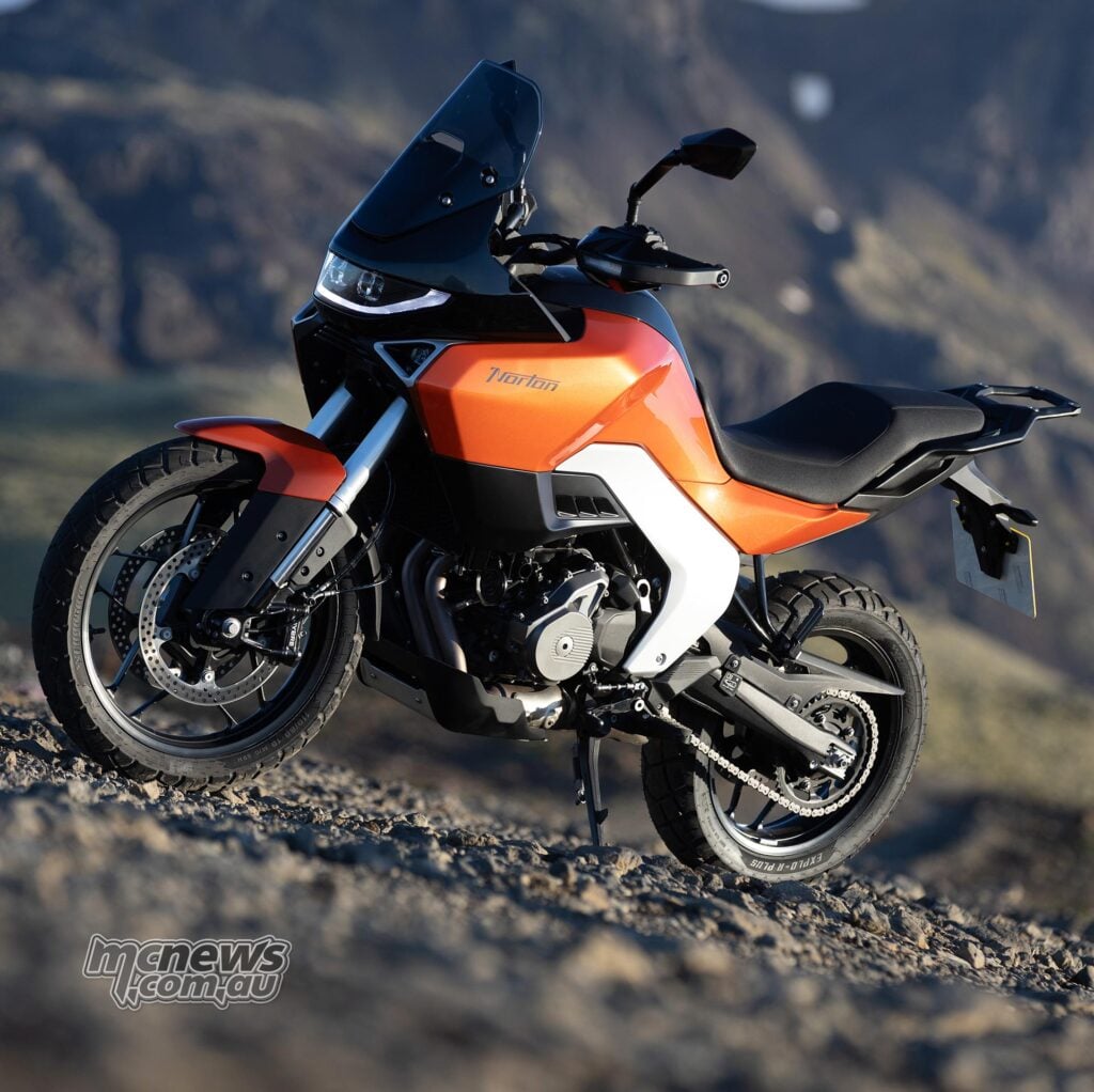 Orange Norton Atlas viewed from the front left, showing its bodywork, 19-inch front wheel and windscreen.