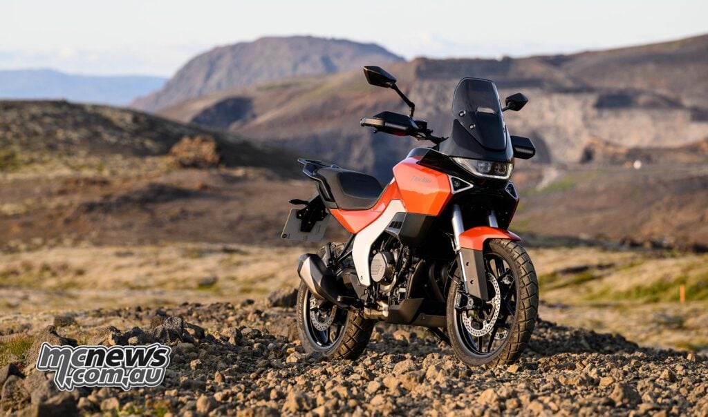 Orange Norton Atlas Apex parked on Icelandic volcanic terrain, viewed from the front right