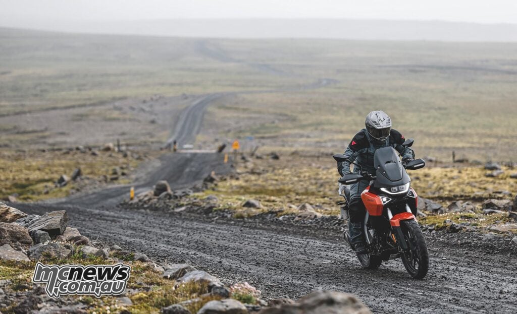 Rider on an orange Norton Atlas travelling across Icelandic gravel terrain.