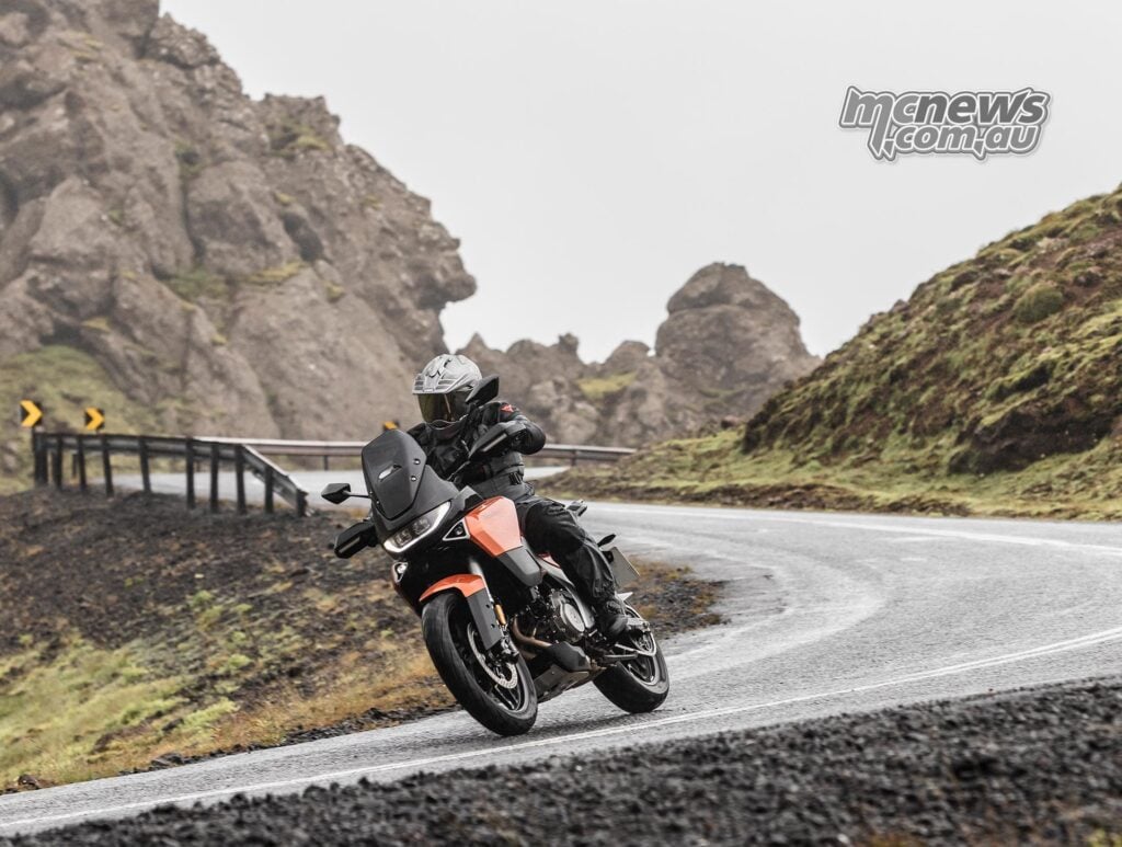 Motorcyclist leaning an orange Norton Atlas through a wet Icelandic corner.