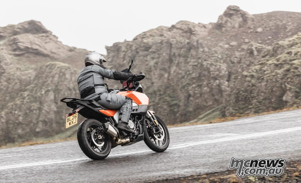 Motorcyclist riding an orange Norton Atlas through the Icelandic landscape.