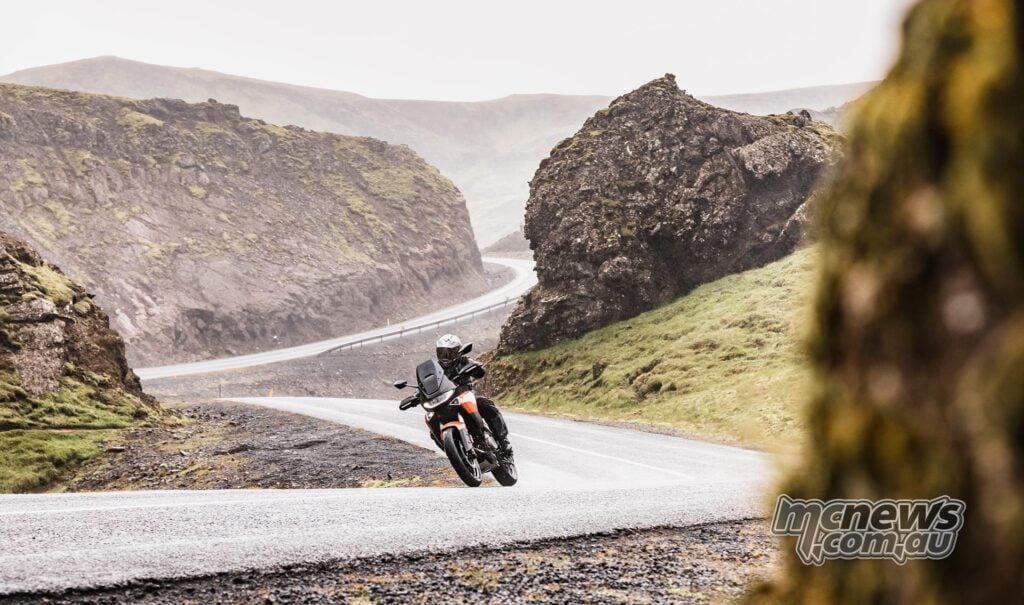 Motorcyclist cornering a Norton Atlas on a wet Icelandic mountain road.