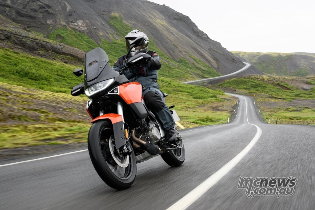 Rider on an orange Norton Atlas travelling across Icelandic terrain.