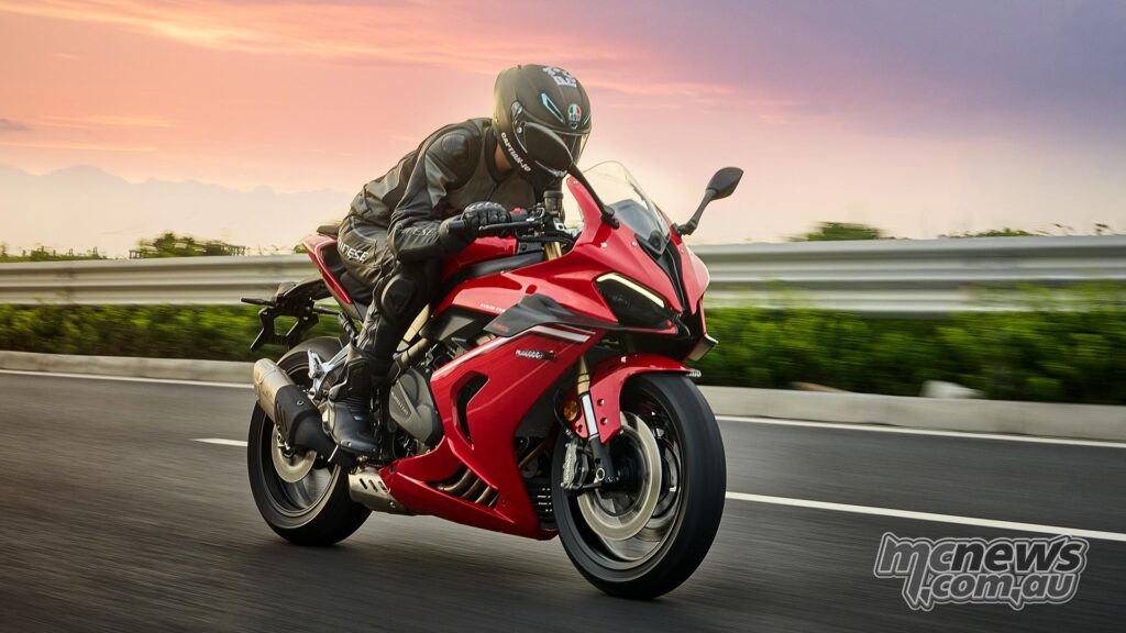 A red QJMOTOR SRK 800 RR sportsbike is being driven on the road.