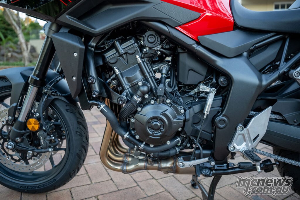 Left side of the Honda CB1000GT engine showing its exhaust headers and quickshifter linkage.