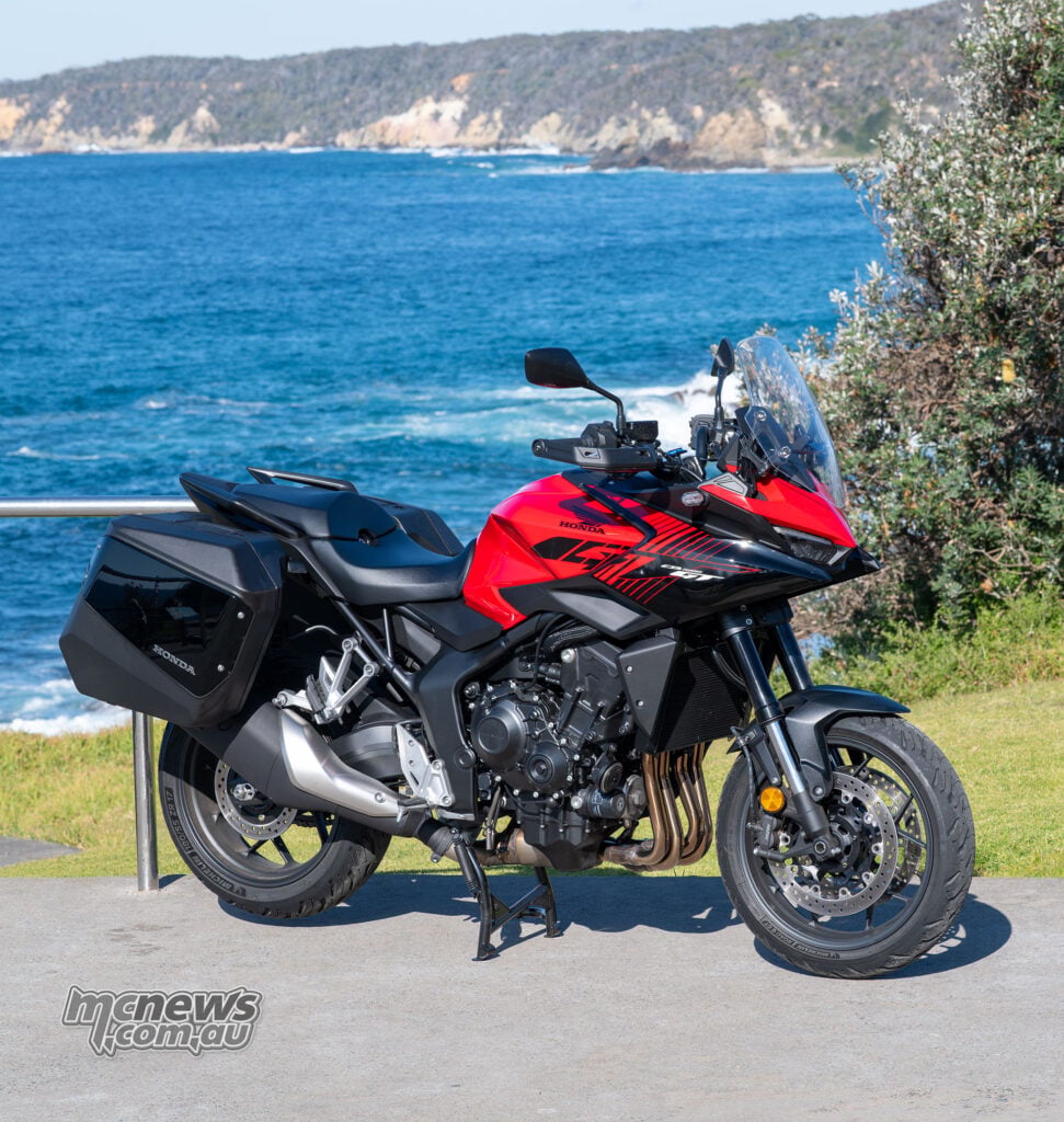Honda CB1000GT with panniers viewed from the front-right beside the ocean.