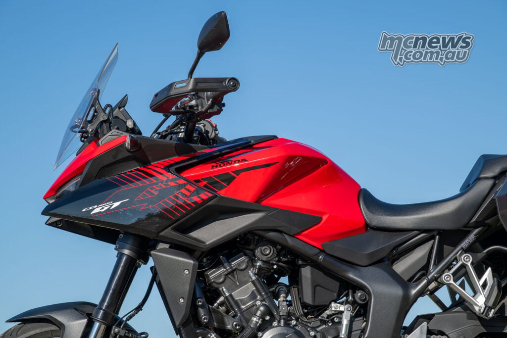 Low-angle view of the red Honda CB1000GT fairing, fuel tank, handlebar and windscreen against blue sky.