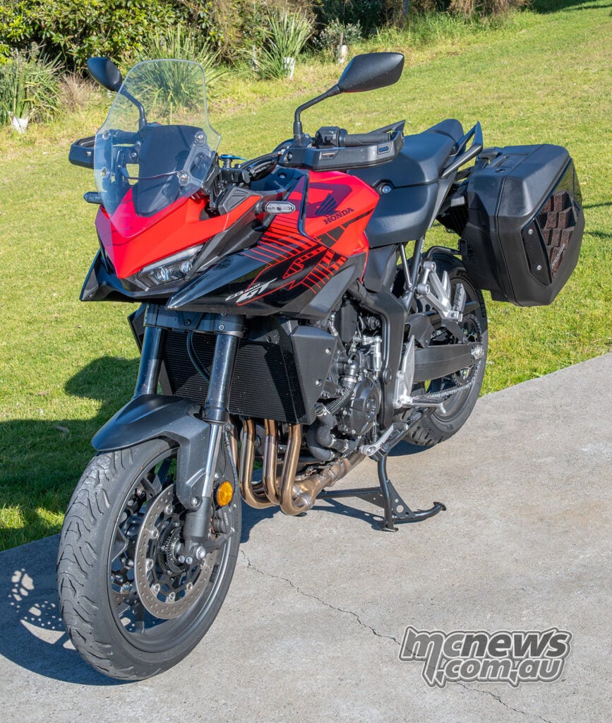 Red Honda CB1000GT viewed from the front-left with panniers, windscreen and centrestand.