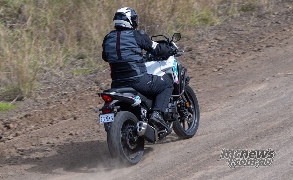 Rear three-quarter view of Trevor Hedge riding a Honda NX500 on gravel