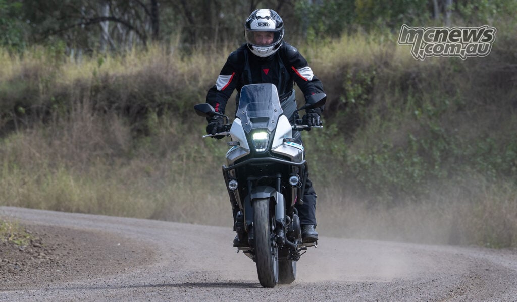 Front view of Trevor Hedge riding a Honda NX500 along a dusty gravel road