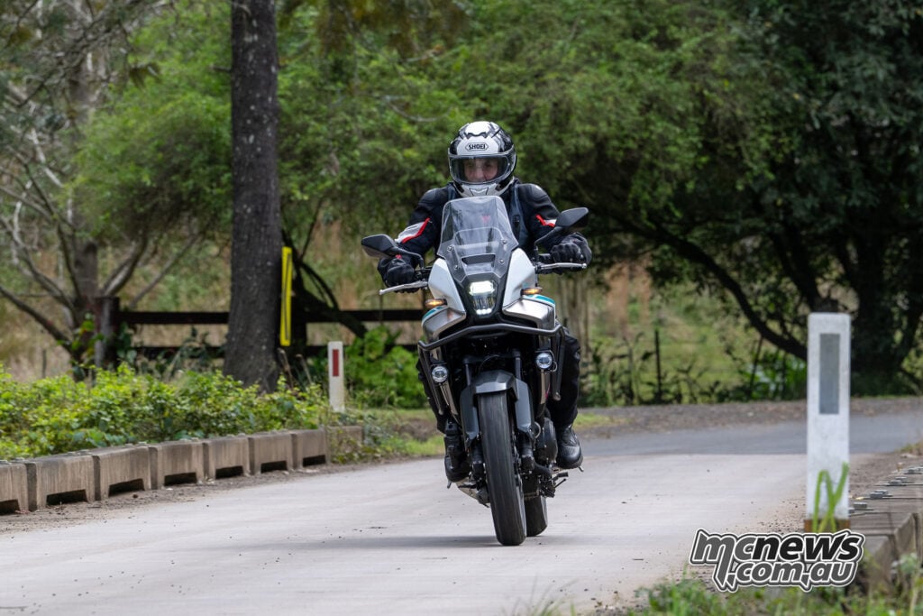 Front view of Trevor Hedge riding a Honda NX500 E-Clutch across a narrow bridge